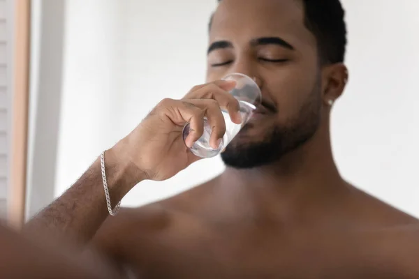 Millennial African man drinking pure clean mineral water indoors — Stock Photo, Image