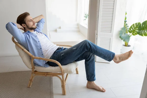 Untroubled millennial hombre soltero relajándose en la silla en el hogar de moda — Foto de Stock