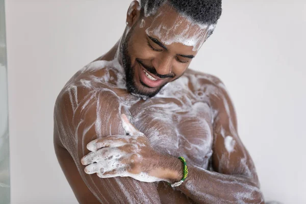 African man takes a shower washes his body with soap — Stock Photo, Image