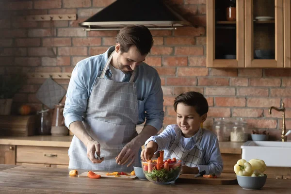 Buon padre e piccolo figlio con i grembiuli che cucinano insieme — Foto Stock