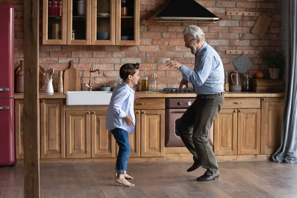 Gelukkig senior grootvader met kleine kleinzoon dansen in de keuken — Stockfoto