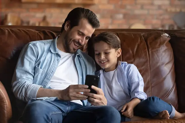 Счастливый отец и маленький сын веселятся со смартфоном — стоковое фото