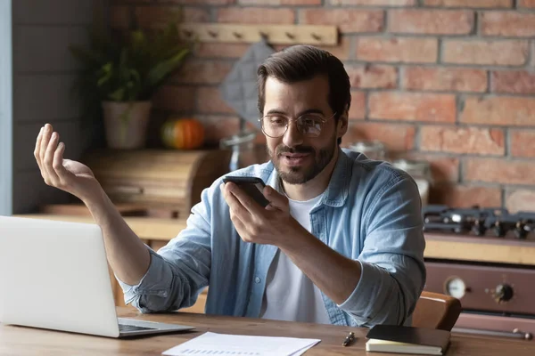 Hombre con gafas sosteniendo el teléfono inteligente, charlando en línea por videollamada —  Fotos de Stock