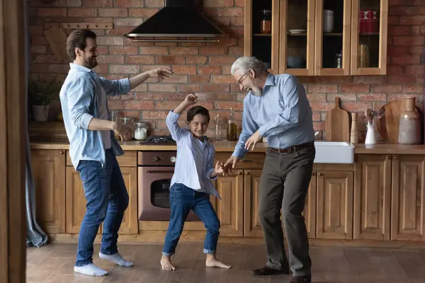 Glücklicher kleiner Junge mit Vater und erwachsenem Großvater beim gemeinsamen Tanzen — Stockfoto