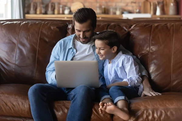 Vårdande far med lille son kramas, använda laptop tillsammans — Stockfoto