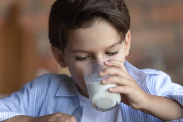 Cerca de 8s niño bebiendo sabrosa leche fresca, sosteniendo el vidrio — Foto de Stock