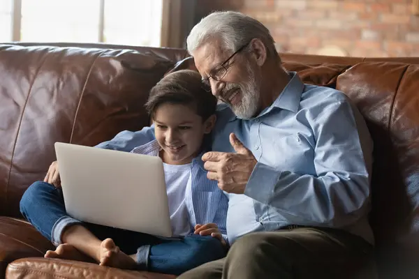 Feliz abuelo mayor con nieto pequeño usando el ordenador portátil juntos — Foto de Stock