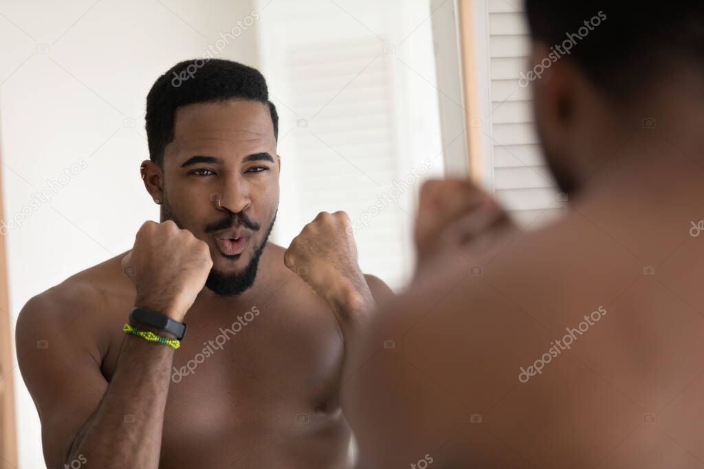 African man clenched fists challenging his own reflection in mirror
