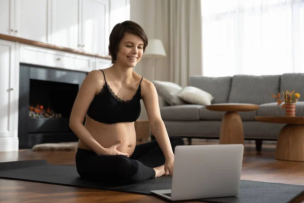 Señora expectante ver clase de yoga para futuras mamás en el ordenador portátil — Foto de Stock