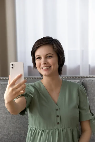 Beautiful female expecting baby sit on couch take cute selfie — Stock Photo, Image