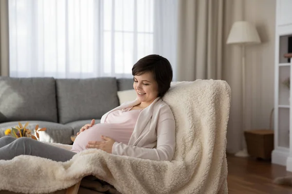 Embarazada mujer relajarse en sillón acariciando la barriga hablando con el bebé — Foto de Stock