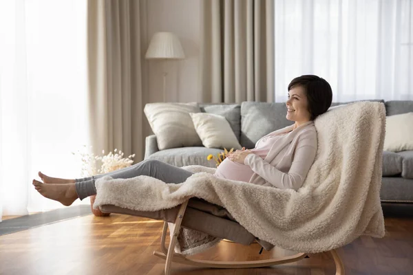 Vreedzame jonge vrouw verwacht moeder liggend op comfortabele schommelstoel — Stockfoto