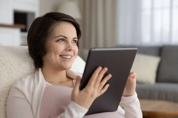 Giovane donna incinta sedersi sulla sedia godere utilizzando pad elettronico — Foto Stock