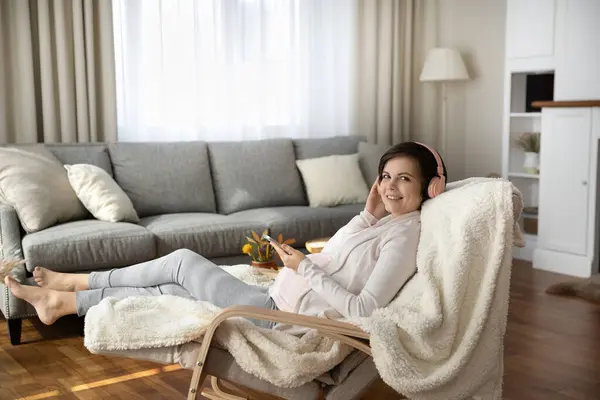 Pregnant female in earphones relax in comfy chair with cell — Stock Photo, Image