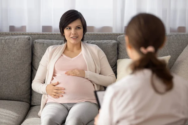 Mladá žena v posledních měsících těhotenství mluví s lékařem — Stock fotografie