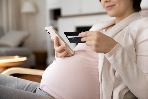 Jovem futura mãe verificar saldo do cartão de crédito usando telefone — Fotografia de Stock