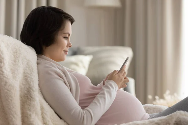 Očekávající maminka sledovat porod videa na telefonu textové zprávy — Stock fotografie