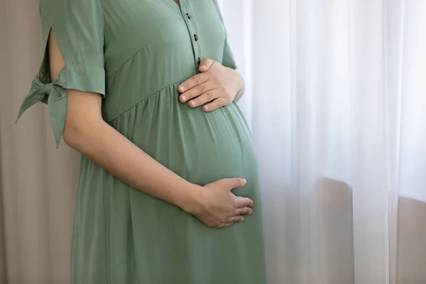 Tender single pregnant woman embrace big tummy by window — Stock Photo, Image