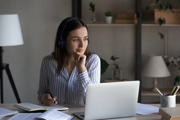 Bedachtzame vrouw in hoofdtelefoon nadenken project, kijken in afstand — Stockfoto