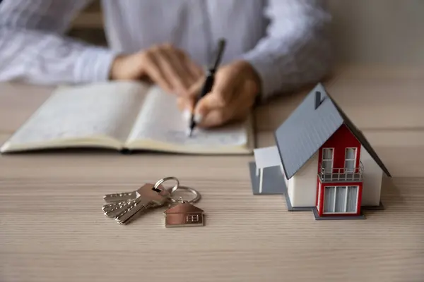 Crop close up Geschäftsfrau Maklerin macht sich Notizen, Papierhaus-Modell — Stockfoto