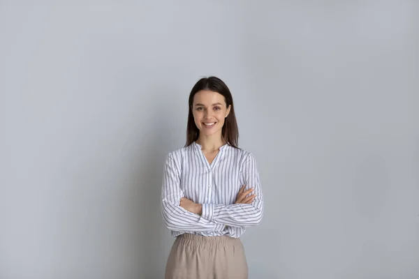 Porträtt säker leende kvinna med armarna korsade på grå bakgrund — Stockfoto