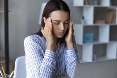 Sağlıksız iş kadını şakaklara dokunuyor, baş ağrısı çekiyor.