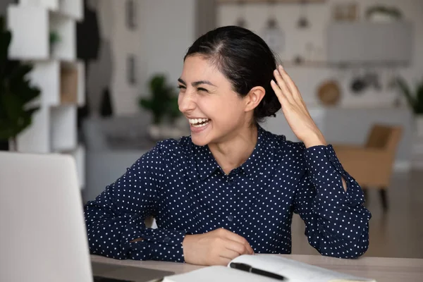 Захоплена індійська жінка сміється, дивиться на екран ноутбука, розмовляє онлайн — стокове фото