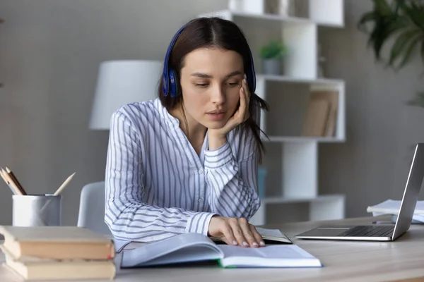 Mulher em fones de ouvido sem fio livro de leitura, estudando em casa — Fotografia de Stock