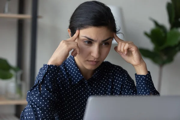 Primer plano pensativa mujer de negocios india tocar templos, utilizando el ordenador portátil — Foto de Stock