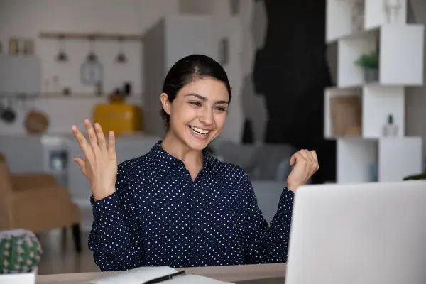 Alegre mujer india sorprendida mirando la pantalla del ordenador portátil, leyendo noticias —  Fotos de Stock