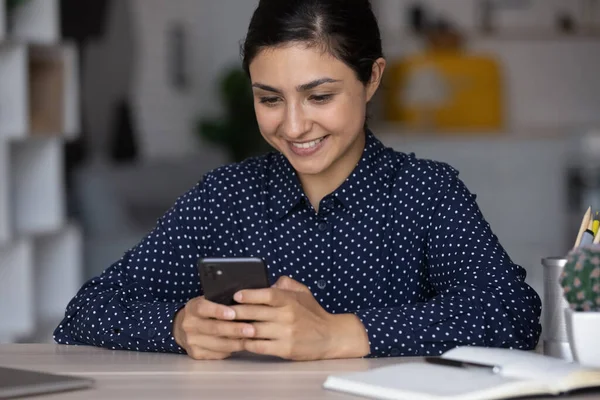 Закрийте посмішку індійській жінці, яка користується смартфоном на роботі. — стокове фото