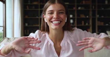 Ekran görüntüsü, kulaklıklı neşeli genç kadın kameranın önünde konuşuyor.