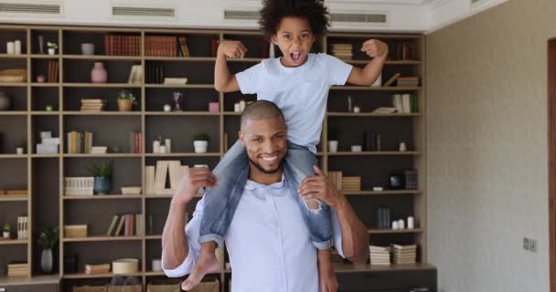 Afrikaanse zoon zitten op sterke vaders schouders demonstreren biceps kracht — Stockvideo