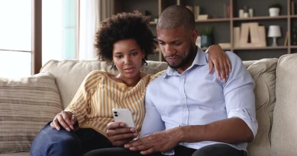 Africano casal sentar no sofá usando telefone inteligente moderno — Vídeo de Stock