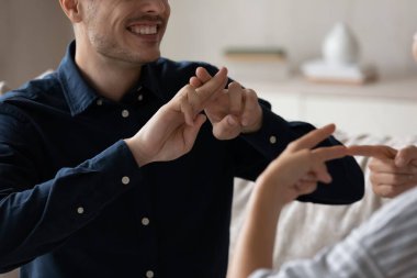 Kesilmiş resmi kapat. Gülümseyen genç çift işaret dili kullanıyor..