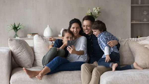 Glad vänlig familj med barn som använder mobiltelefon. — Stockfoto