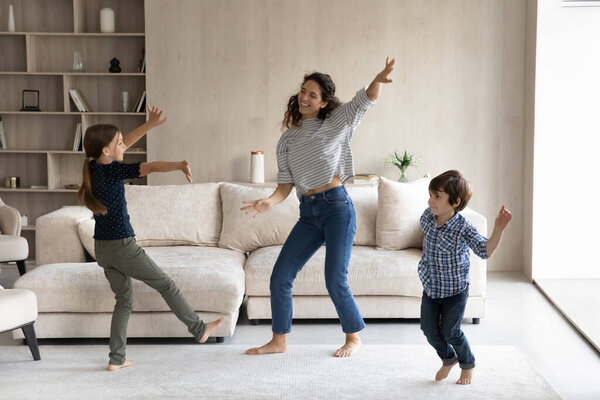 Young hispanic mother dancing with small children.