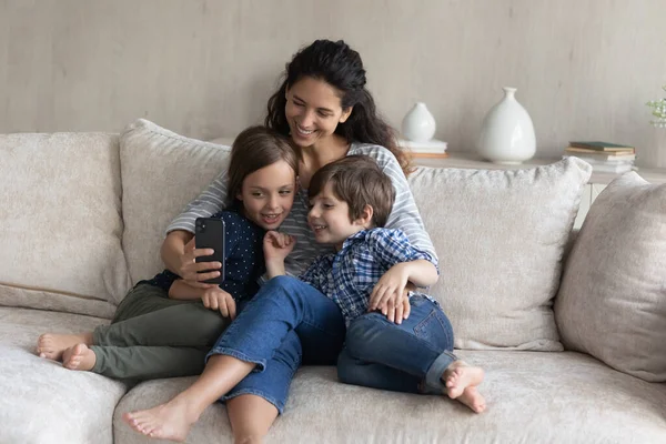 Feliz jovem mãe e crianças pequenas posando para selfie no celular. — Fotografia de Stock