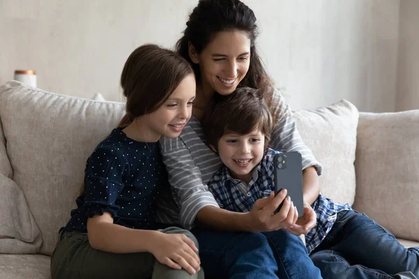 Famille heureuse utilisant un téléphone portable le week-end à la maison. — Photo