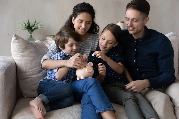 Casal feliz pais ensinando crianças pequenas filho filha economizando dinheiro. — Fotografia de Stock