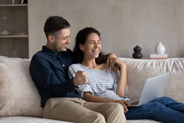 Glückliches junges Familienpaar nutzt Computer zu Hause. — Stockfoto