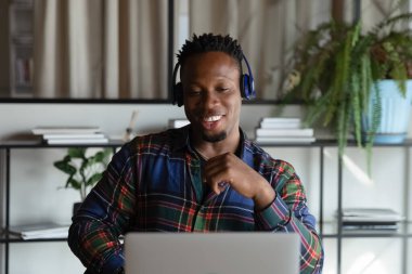 Mutlu Afrikalı Amerikalı hippi öğrenci kulaklıklı adam Webinar izliyor.