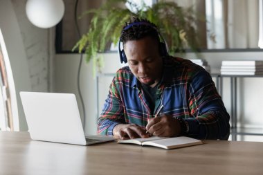 Kulaklıklı ciddi bir Afrikalı Amerikalı öğrenci Webinar izliyor.