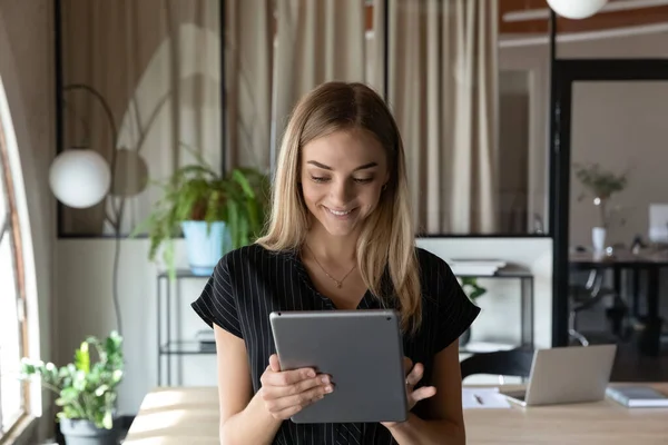 Щаслива бізнес-леді, використовуючи онлайн-додаток на планшеті в офісі — стокове фото