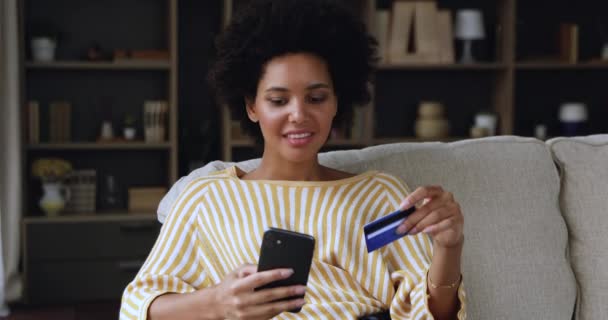 Joven mujer negro titular de la tarjeta de crédito pagar en línea utilizando el teléfono — Vídeo de stock