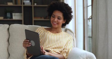 Genç melez kadın rahat koltukta elektronik dokunmatik ped kullanarak rahatlıyor.