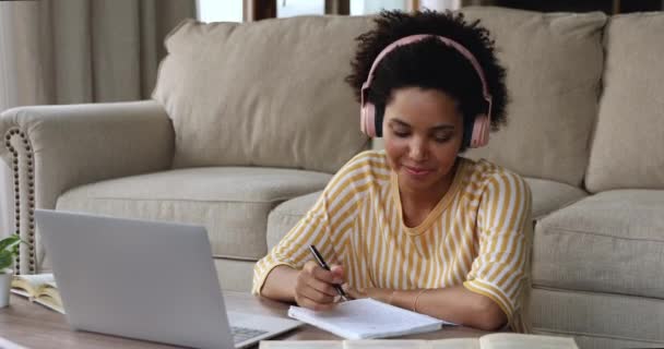 Женщина-подросток в наушниках изучает наушники из дома с помощью ноутбука — стоковое видео