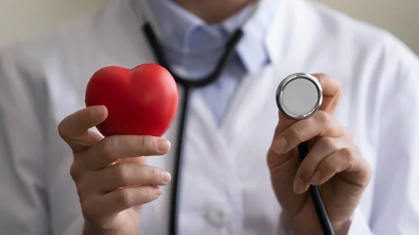 Joven cardióloga sosteniendo corazón rojo y estetoscopio — Foto de Stock
