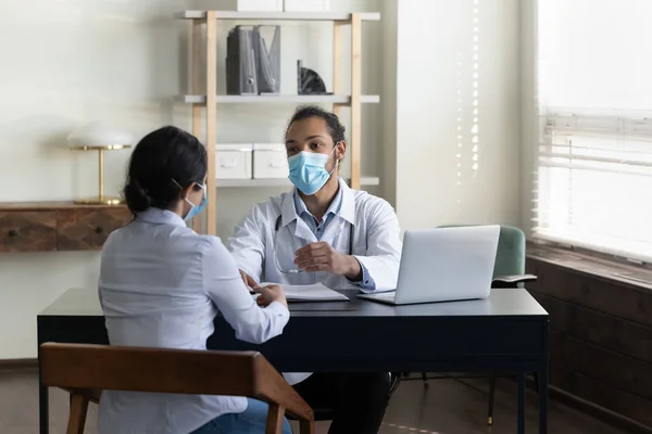 Giovane maschio razza mista medico in maschera incontro con il paziente — Foto Stock