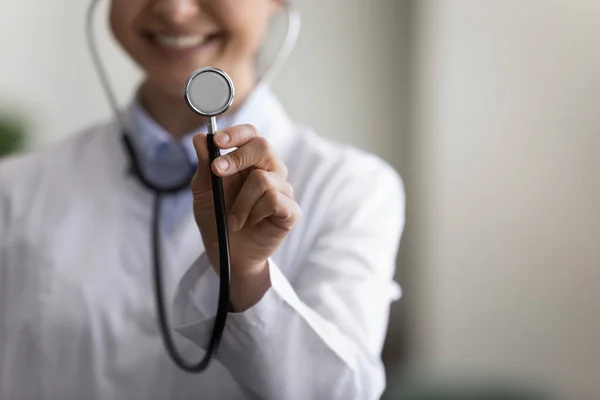 Jovem médico feliz GP usando estetoscópio, mostrando ferramenta na câmera — Fotografia de Stock